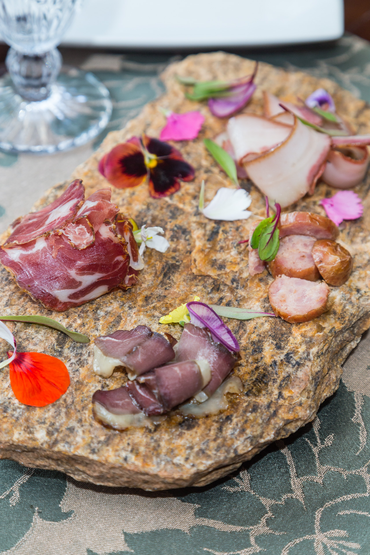 Tábua de curados sobre pedra com flores comestíveis